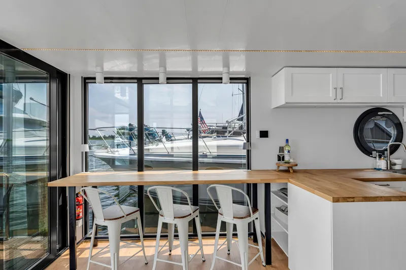 Slide: The Image of Modern Waterlodge Apart L Long 2026 interior with kitchen, bar stools, and waterfront view. - 9