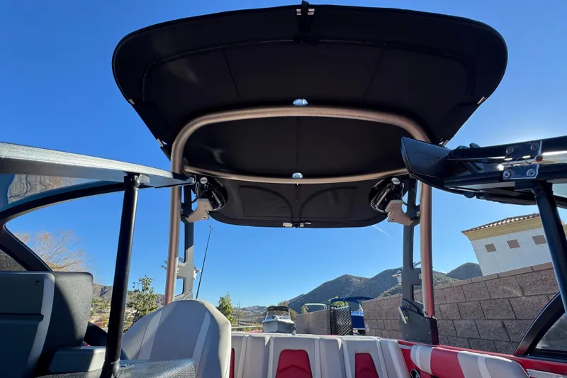 Slide: The Image of 2018 Malibu Wakesetter 21 MLX boat interior with canopy, mountain view background. - 10