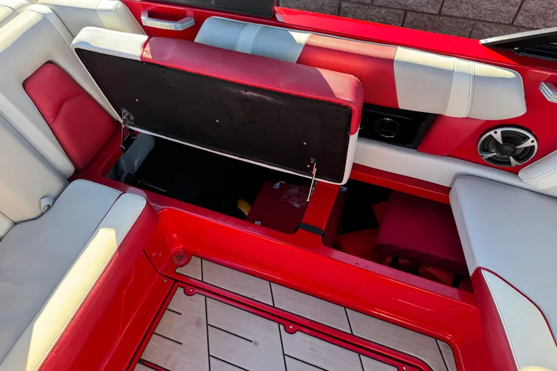 Slide: The Image of 2018 Malibu Wakesetter 21 MLX interior with red and gray seating, open storage compartment. - 24