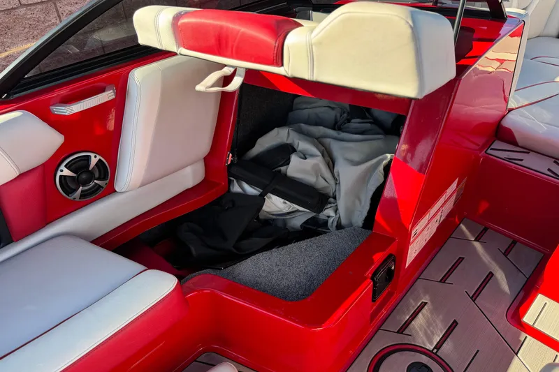 Slide: The Image of 2018 Malibu Wakesetter 21 MLX interior with red and white seating and storage compartment. - 26