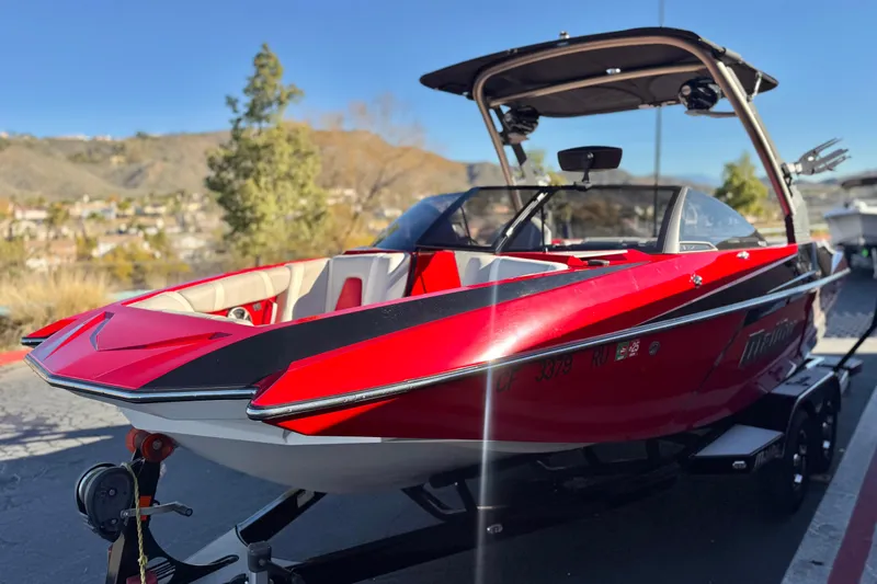 Slide: The Image of 2018 Malibu Wakesetter 21 MLX boat, red exterior, parked on trailer, scenic background. - 3