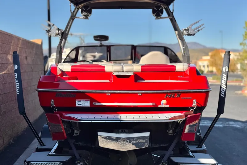 Slide: The Image of 2018 Malibu Wakesetter 21 MLX boat, rear view, vibrant red color, parked outdoors. - 4