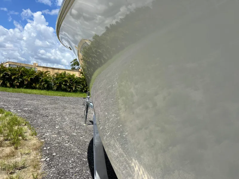Slide: The Image of 2021 Sailfish 242 CC boat side view with clear sky and greenery. - 7