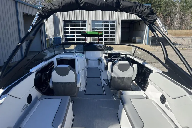 Slide: The Image of 2025 Yamaha Boats AR250 interior with modern seating and controls, docked near a garage. - 11