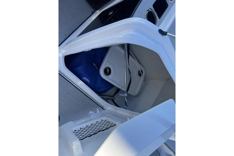 Slide: The Image of 2025 Yamaha Boats AR250 storage compartment with blue cover and netting. - 17