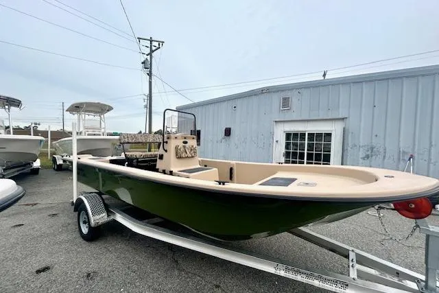 Slide: The Image of 2026 Carolina Skiff E20 JVX CC boat on trailer, parked outside a building. - 2