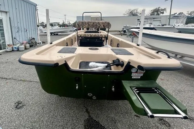 Slide: The Image of 2026 Carolina Skiff E20 JVX CC boat, green and beige, rear view in a marina setting. - 9