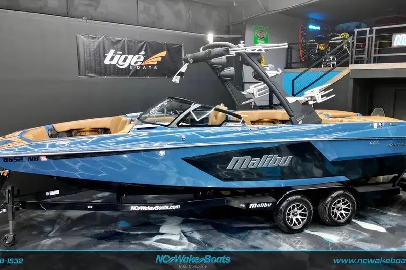 The Image of 2024 Malibu Wakesetter 24 MXZ boat in showroom, blue exterior, on trailer. - 1