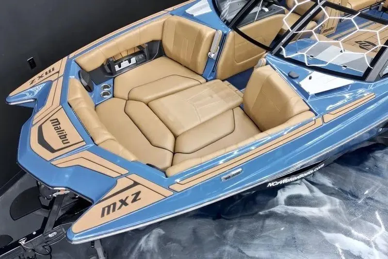 Slide: The Image of 2024 Malibu Wakesetter 24 MXZ boat interior with tan seating and blue accents. - 5