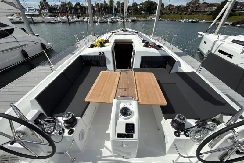 Slide: The Image of 2025 Jeanneau Sun Odyssey 440 sailboat cockpit with dual steering wheels and wooden table. - 35