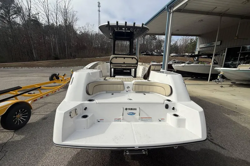 Slide: The Image of 2024 Yamaha Boats 255 FSH Sport E, rear view at dealership, showcasing spacious deck. - 14