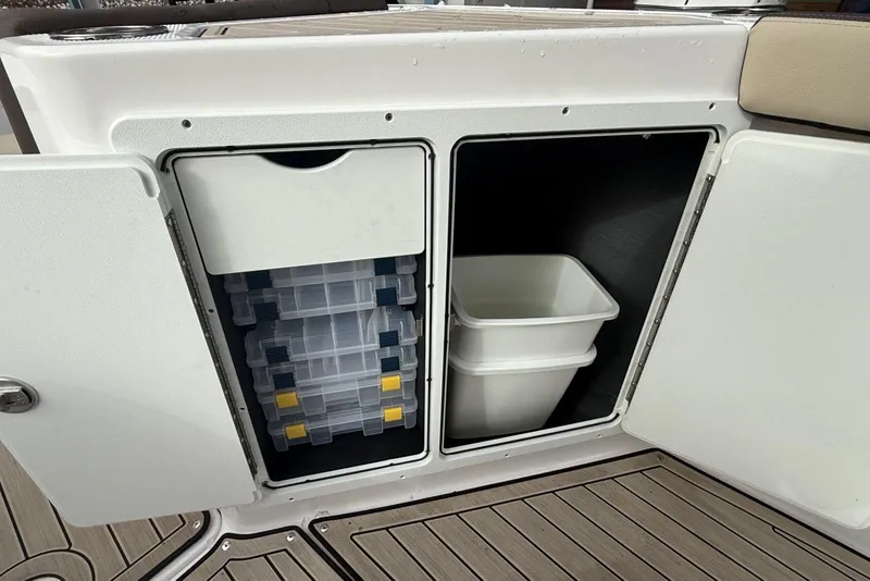 Slide: The Image of 2024 Yamaha Boats 255 FSH Sport E storage compartments with tackle boxes and bins. - 18