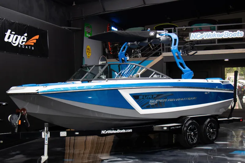 The Image of 2018 Nautique Super Air Nautique GS22 boat displayed indoors on a trailer. - 1