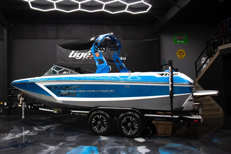 Slide: The Image of 2018 Nautique Super Air Nautique GS22 boat in showroom, blue and white design. - 3