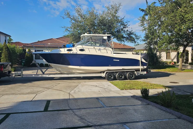 The Image of 2005 Seaswirl Striper 290 boat on trailer in residential driveway. - 0