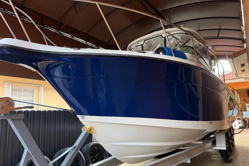 Slide: The Image of 2005 Seaswirl Striper 290 boat on trailer under canopy, blue and white hull. - 3