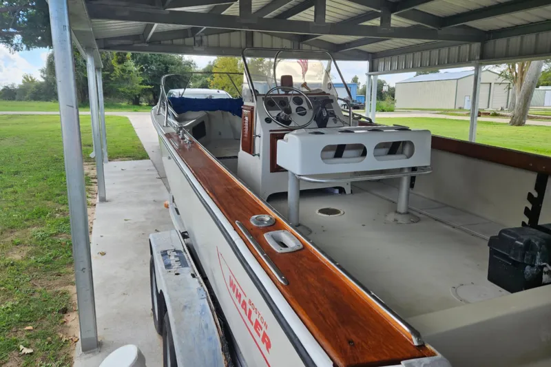 Slide: The Image of 1980 Boston Whaler Outrage 20 boat under a metal canopy, showcasing interior and steering console. - 5