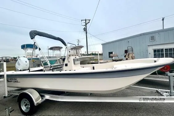 Slide: The Image of 2026 Carolina Skiff E20 JVX CC boat on trailer, parked outdoors near a building. - 3