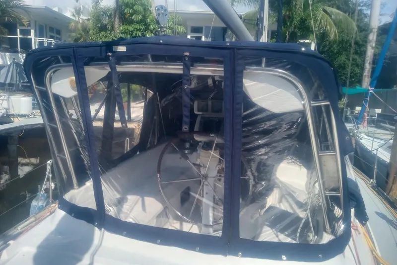 Slide: The Image of 1997 Hunter Passage 42 sailboat cockpit with protective enclosure, docked near tropical foliage. - 8