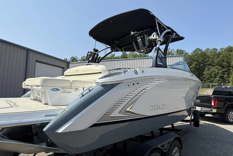 Slide: The Image of 2020 Cobalt R5 Surf boat on trailer, parked outdoors near industrial buildings. - 35