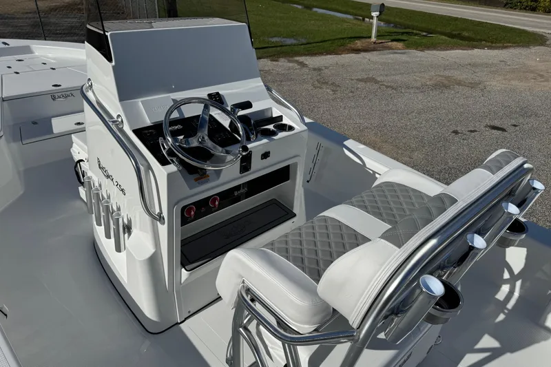 Slide: The Image of 2026 BlackJack 256 Bay boat interior with steering console and cushioned seating. - 13