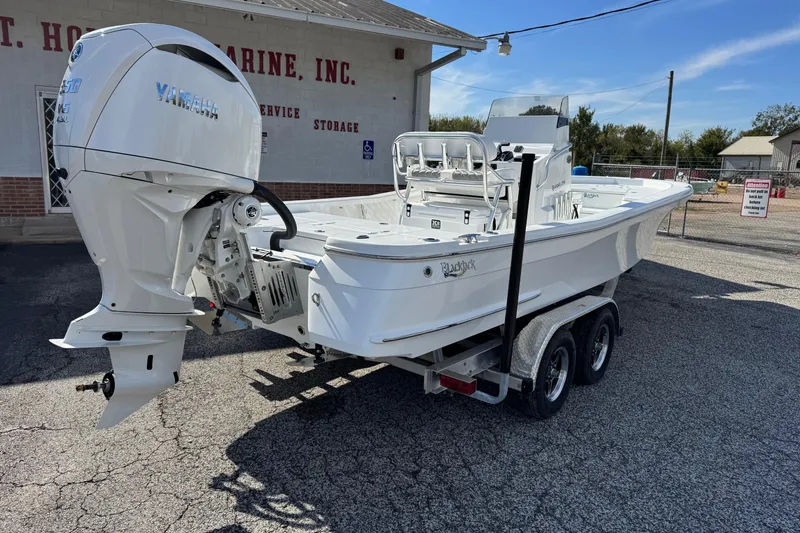 Slide: The Image of 2026 BlackJack 256 Bay boat on trailer with Yamaha outboard motor, parked outside a marine store. - 3