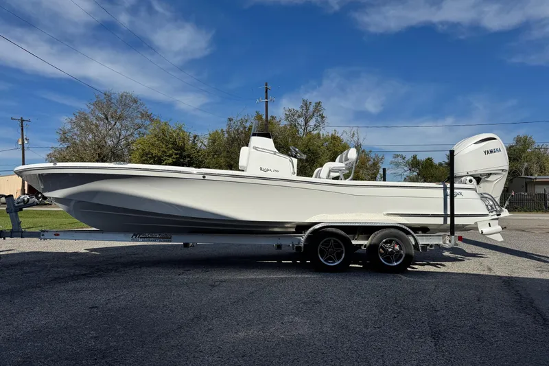 Slide: The Image of 2026 BlackJack 256 Bay boat on trailer, parked outdoors under clear blue sky. - 7
