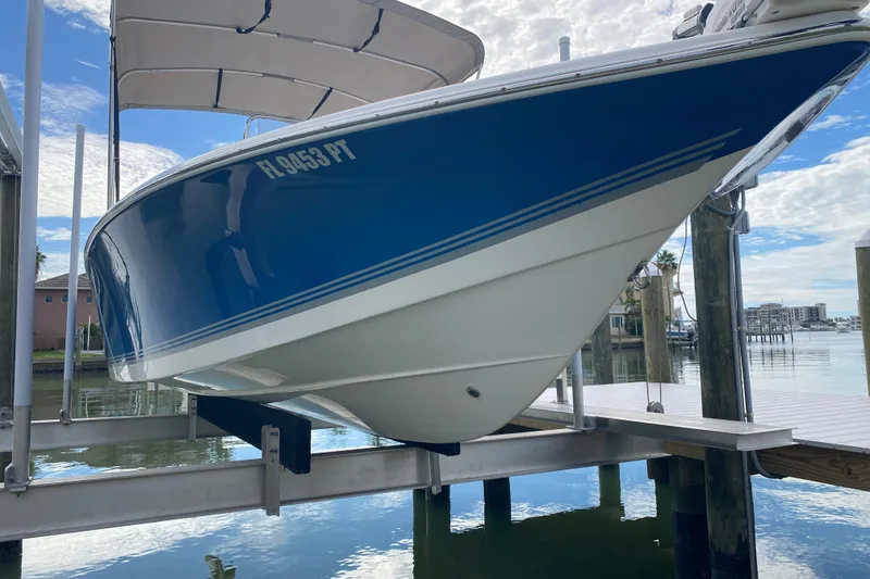 Slide: The Image of Blue and white 2004 Palmetto 22 Excursion boat on a lift by the water. - 12