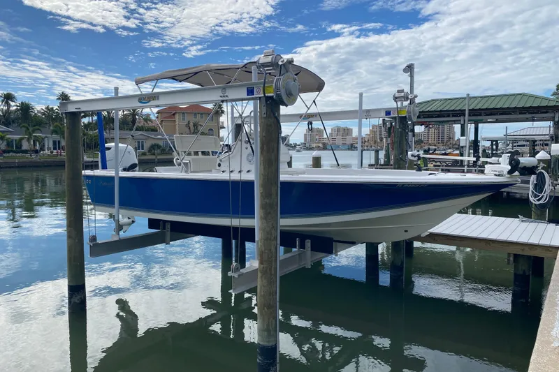 Slide: The Image of 2004 Palmetto 22 Excursion boat on lift at marina, under blue sky. - 13