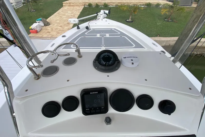 Slide: The Image of 2004 Palmetto 22 Excursion boat dashboard with controls and compass, docked near a garden. - 40