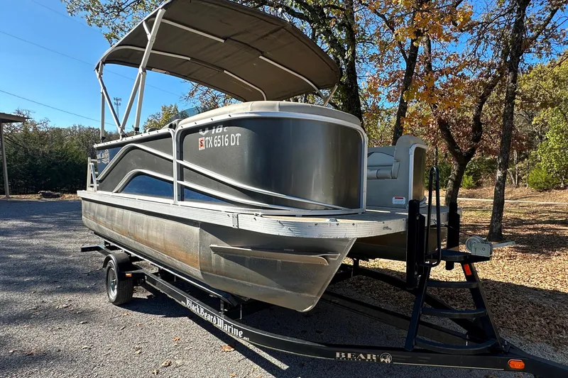 Slide: The Image of 2017 SunCatcher V18 Cruise pontoon boat on trailer, parked in wooded area. - 2