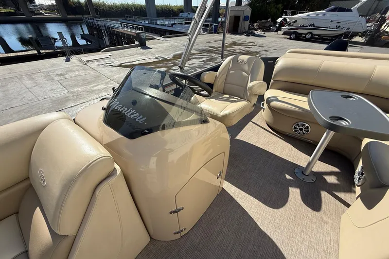 Slide: The Image of 2017 Manitou 230 boat interior with beige seating and steering console. - 11