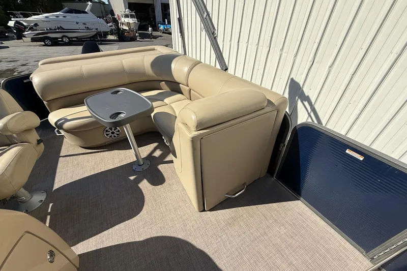 Slide: The Image of 2017 Manitou 230 pontoon boat interior with beige seating and table. - 12