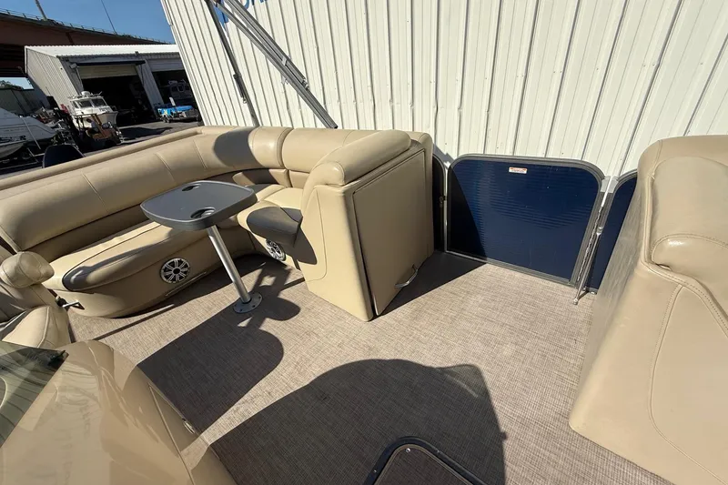 Slide: The Image of 2017 Manitou 230 pontoon boat interior with beige seating and table. - 13