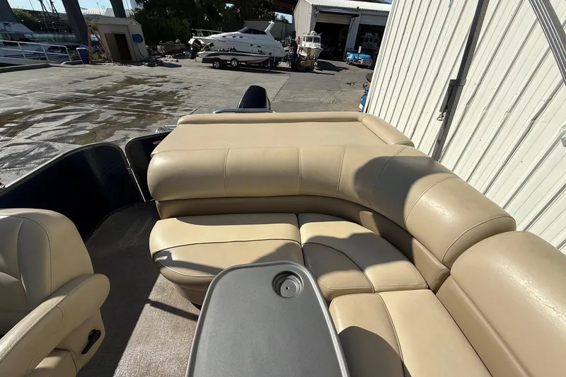 Slide: The Image of 2017 Manitou 230 boat interior with beige leather seating in a marina setting. - 14
