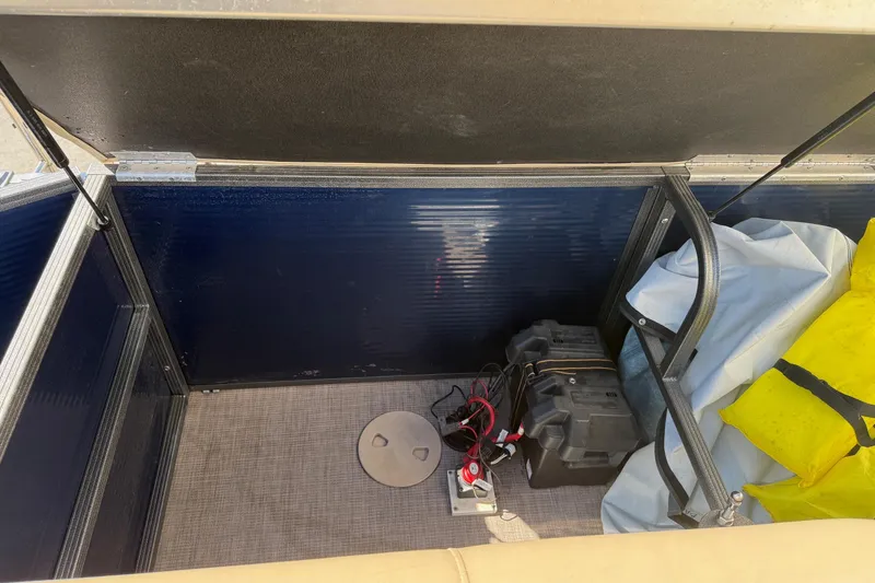 Slide: The Image of Storage compartment of a 2017 Manitou 230 boat with battery and equipment. - 19