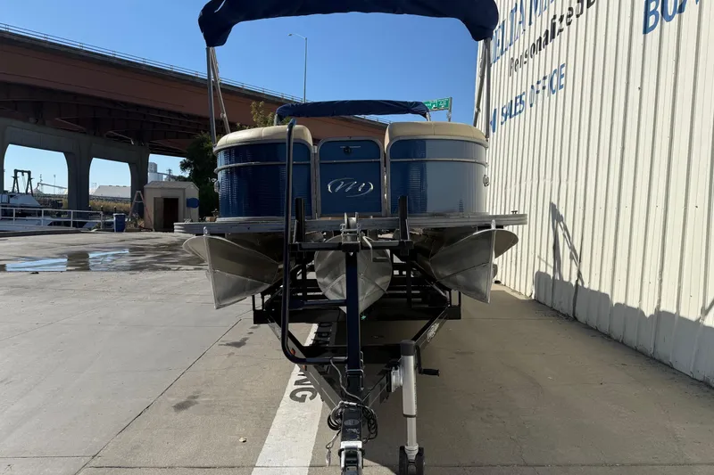Slide: The Image of 2017 Manitou 230 pontoon boat on trailer near industrial area. - 2