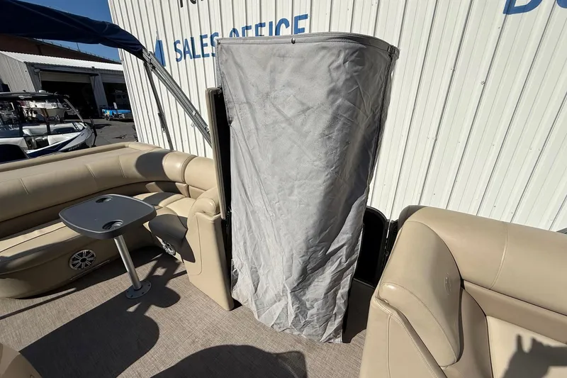 Slide: The Image of 2017 Manitou 230 boat interior with beige seating and a covered area. - 20