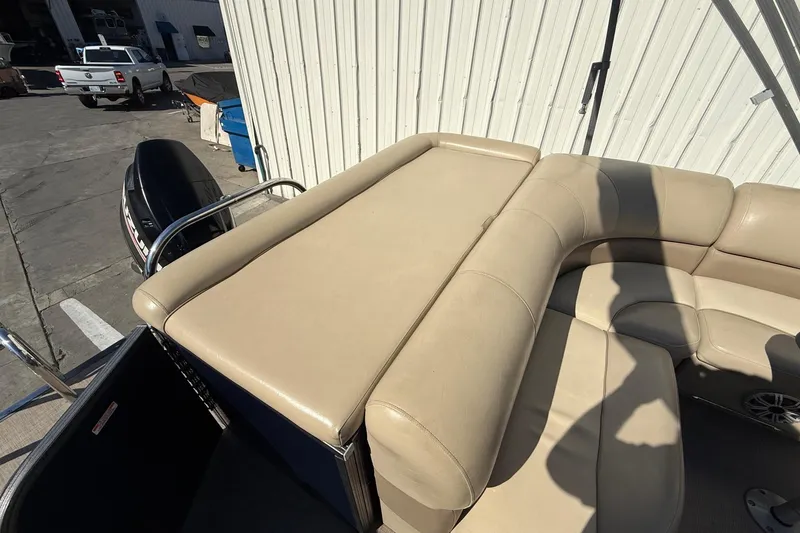 Slide: The Image of 2017 Manitou 230 boat with beige seating and outboard motor in a marina setting. - 21