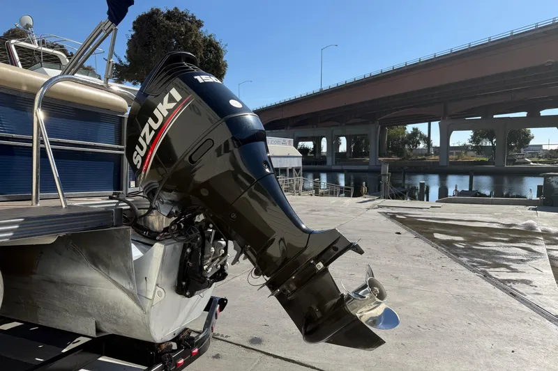 Slide: The Image of 2017 Manitou 230 boat with Suzuki outboard motor at a dockside ramp. - 5