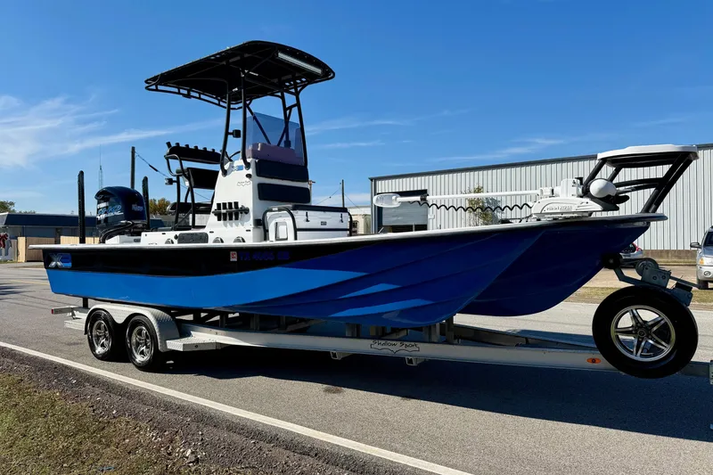 Slide: The Image of 2018 Shallow Sport 25 X3 boat on trailer, blue hull, parked outdoors. - 5