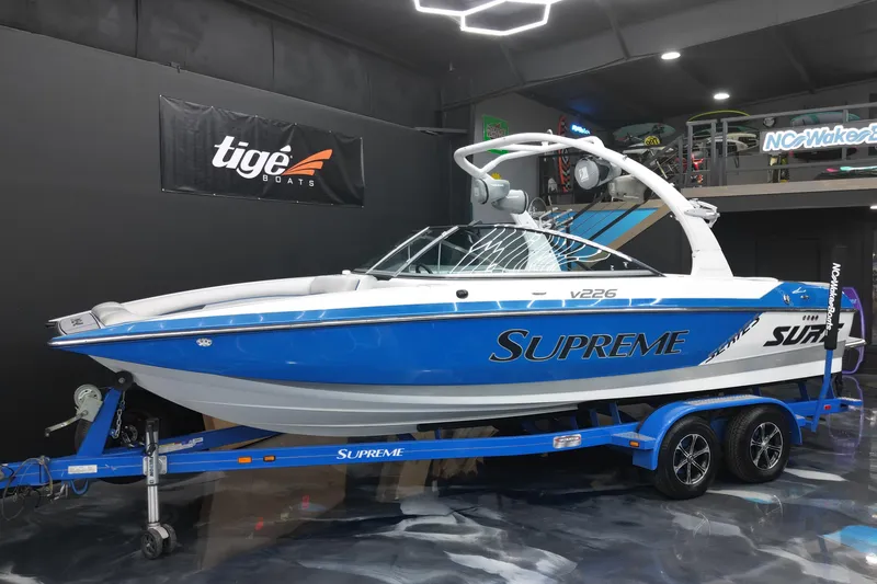 The Image of 2012 Supreme V226 boat in showroom, blue and white design, on trailer. - 1