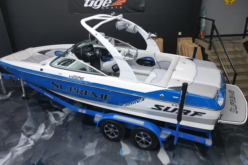 Slide: The Image of 2012 Supreme V226 boat in showroom, blue and white design, on trailer. - 16
