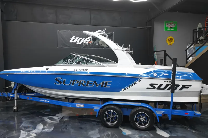Slide: The Image of 2012 Supreme V226 boat in showroom, blue and white design, on trailer. - 3