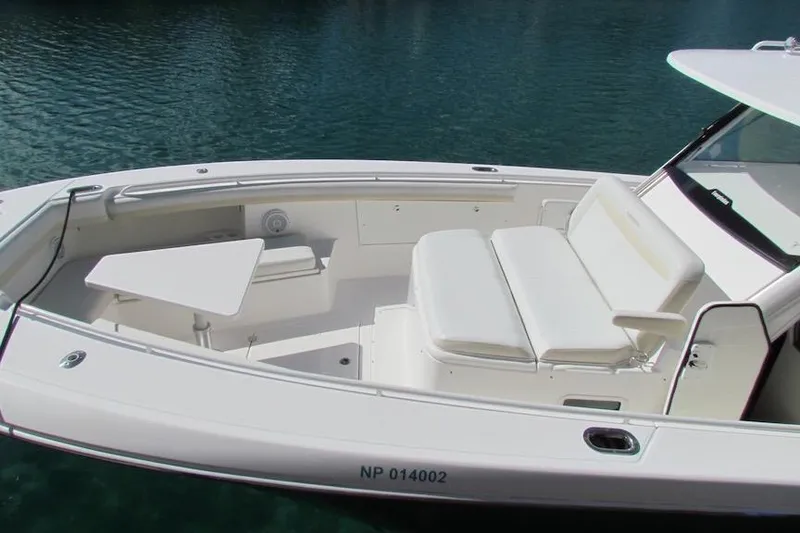 Slide: The Image of 2016 Everglades 435 Center Console boat with white seating and table on calm water. - 12