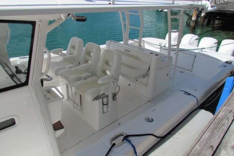 Slide: The Image of 2016 Everglades 435 Center Console boat with white seating, docked by clear blue water. - 20