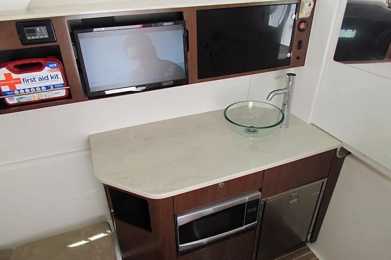 Slide: The Image of 2016 Everglades 435 Center Console interior with sink, TV, and first aid kit. - 31