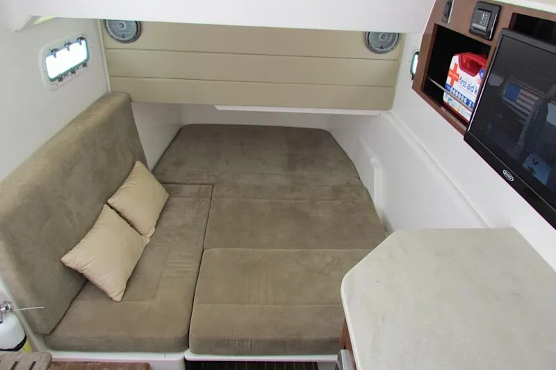 Slide: The Image of 2016 Everglades 435 Center Console cabin interior with beige seating and pillows. - 32