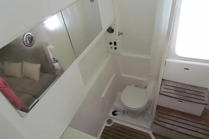 Slide: The Image of Interior of 2016 Everglades 435 Center Console boat, featuring a compact bathroom with toilet and mirror. - 36