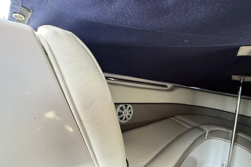Slide: The Image of Interior of a 2004 Cobalt 250 boat with white leather seating and blue canopy. - 13